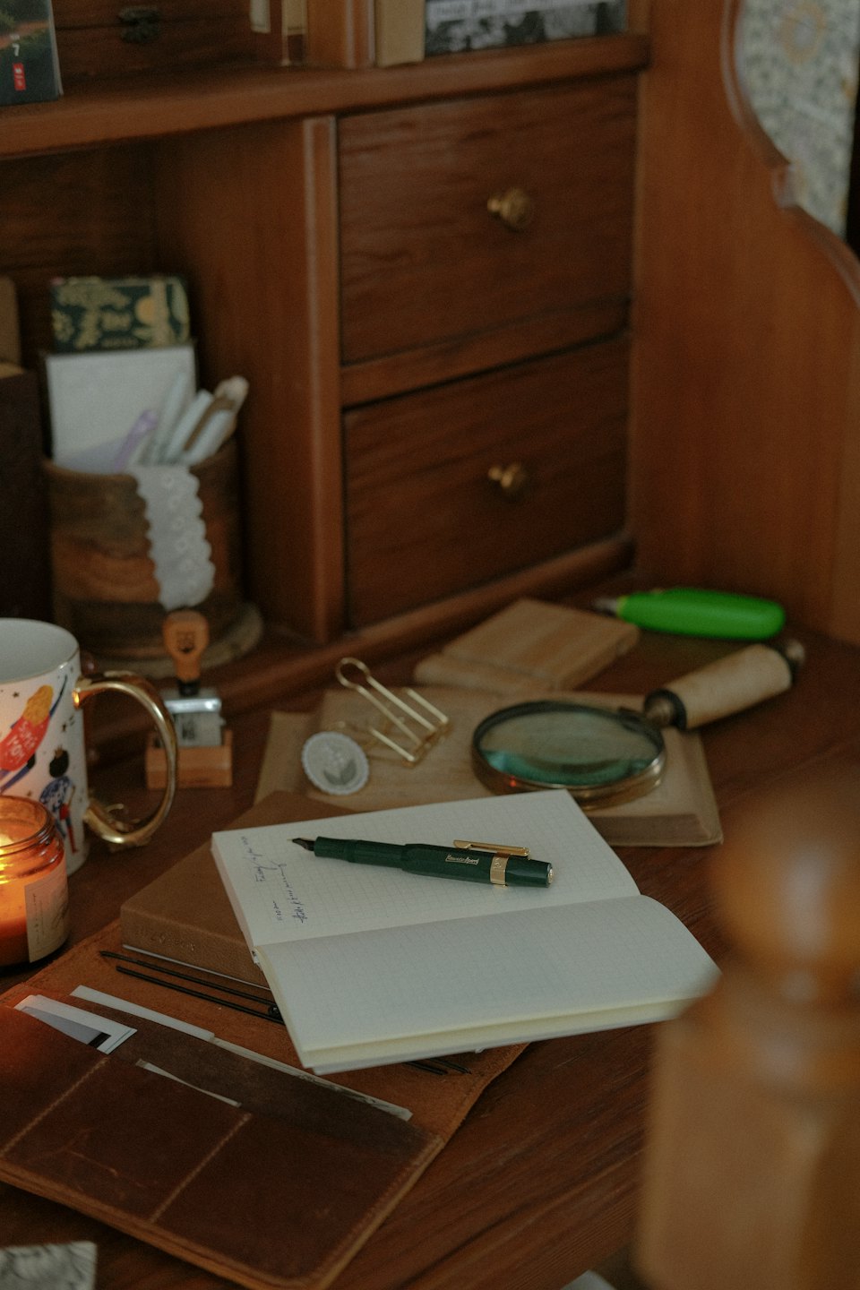 Wooden desk with open notebook, pen, and writing accessories.